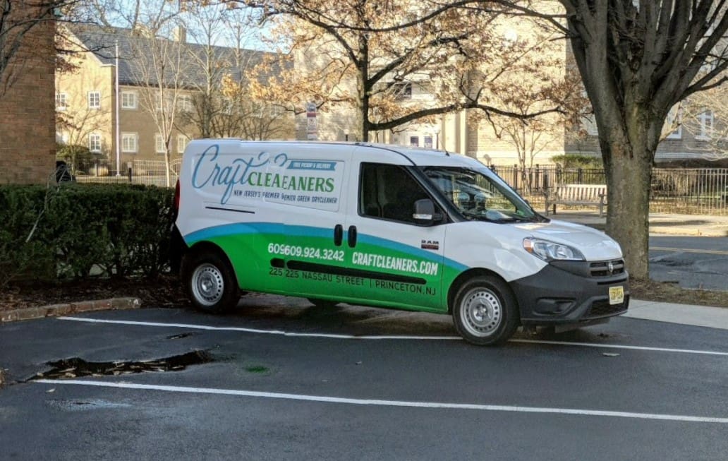 Craft Cleaners delivery van parked outside, featuring branding and contact information, promoting pickup and delivery laundry services.