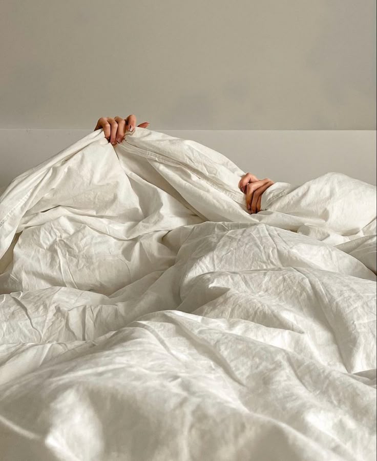 Person's hands holding a wrinkled white duvet, emphasizing comfort and cleanliness in household textiles.